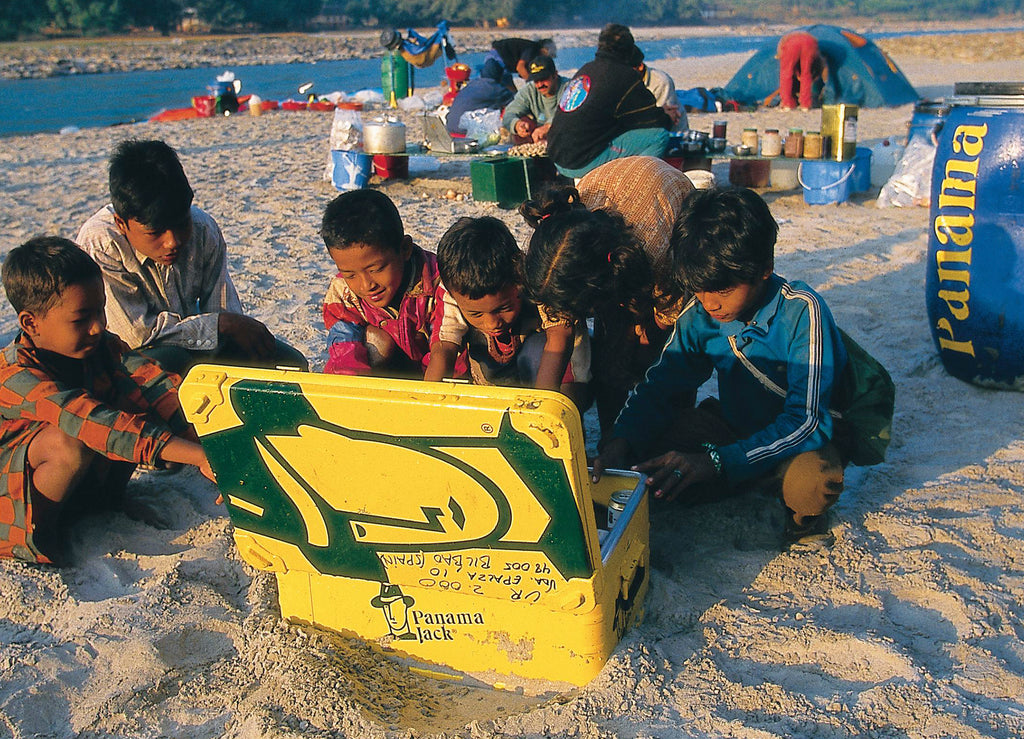Niños en una playa abriendo un baúl de Panama Jack